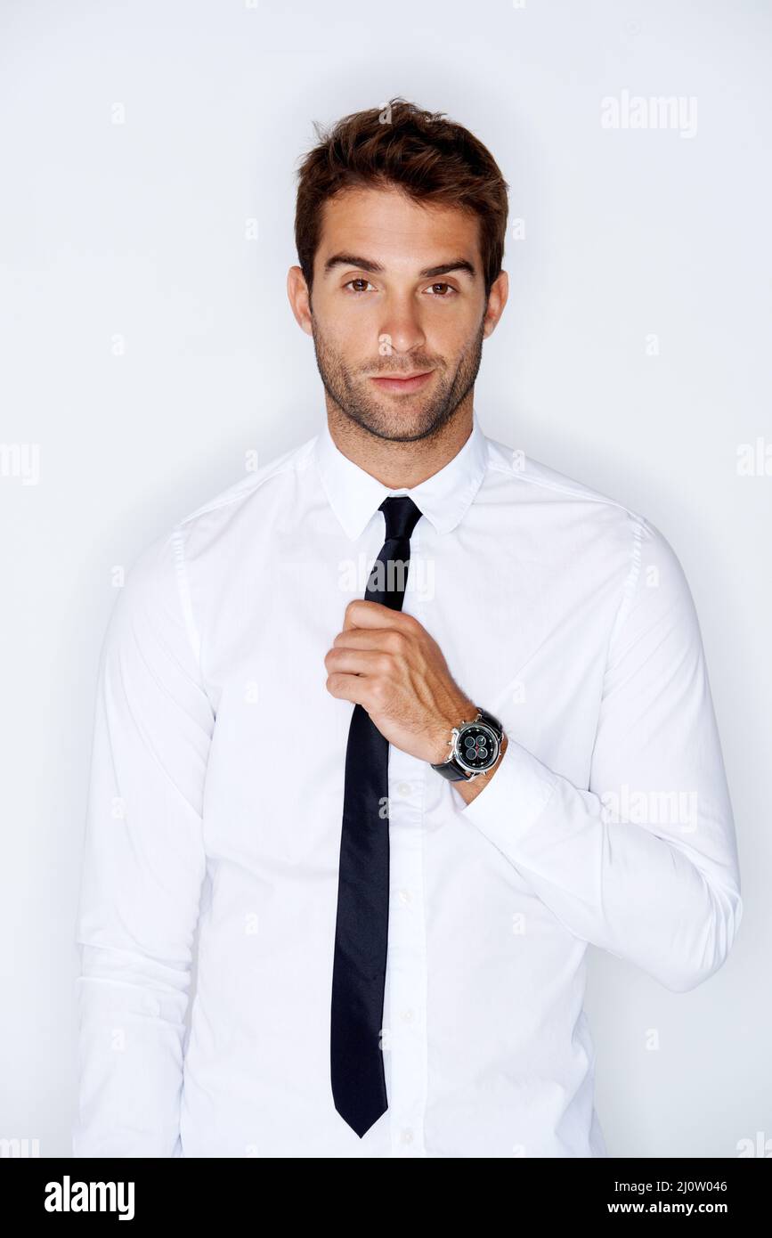 Adjusting his tie. Handsome young guy adjusting his tie against a white ...