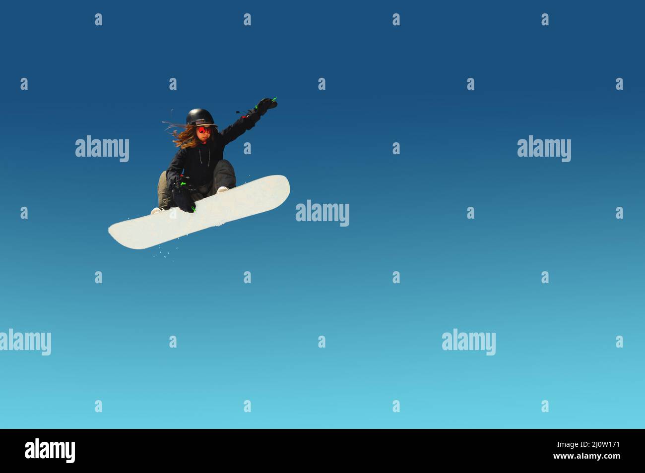 Girl snowboarder in flight after jumping amid blue sky gradient blank designer winter snowboarding sport Stock Photo