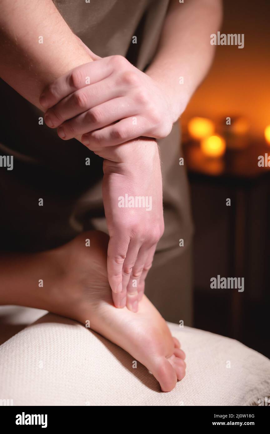 https://c8.alamy.com/comp/2J0W18G/massage-of-human-legs-close-up-professional-foot-massage-in-the-spa-salon-with-dimmed-light-against-the-background-of-burning-c-2J0W18G.jpg