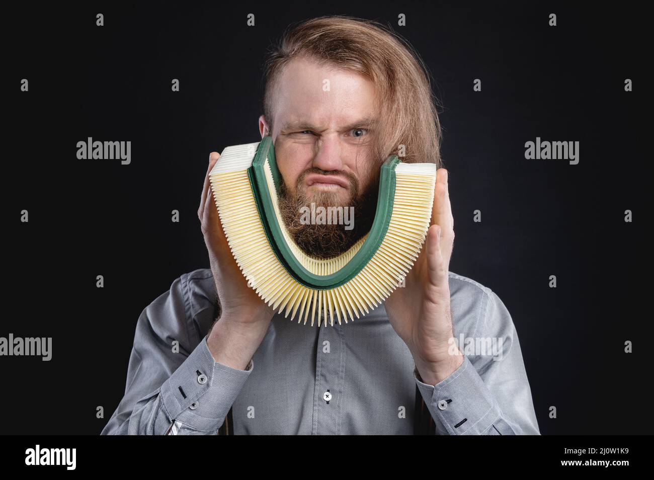 Portrait of a stylish bearded long-haired male salesman and dealer spare parts of the car in a shirt and suspenders. holds the e Stock Photo