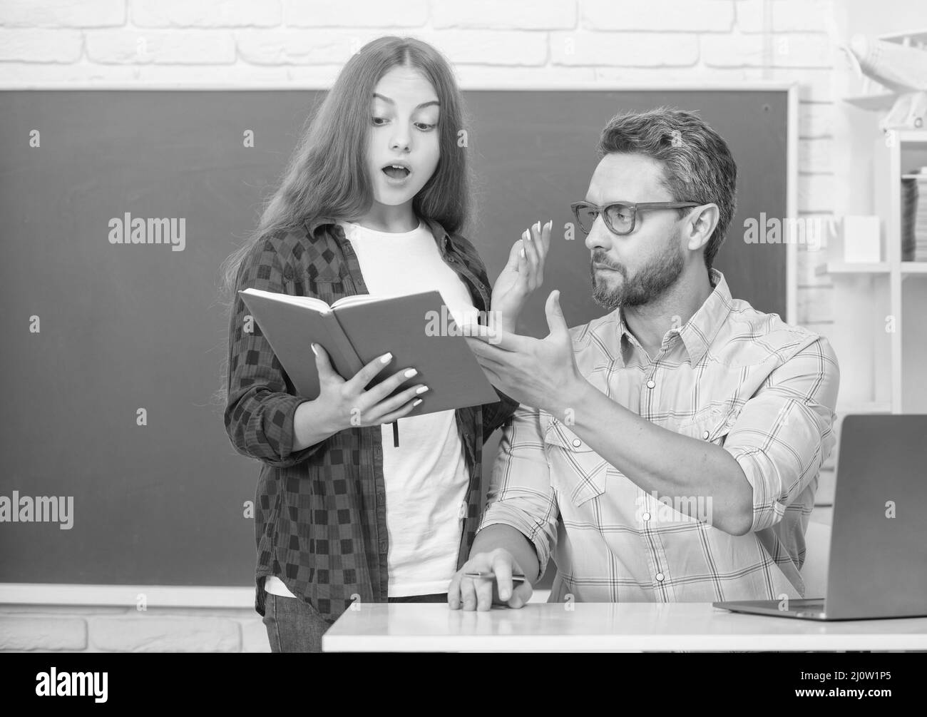 Amazed Teen Girl And Teacher Man In High School With Workbook At