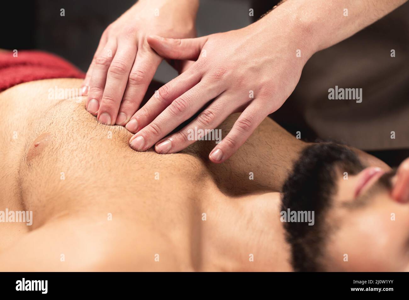 A professional therapist massages the pectoral muscle of an athlete to a man in a professional massage salon. The concept of pro Stock Photo