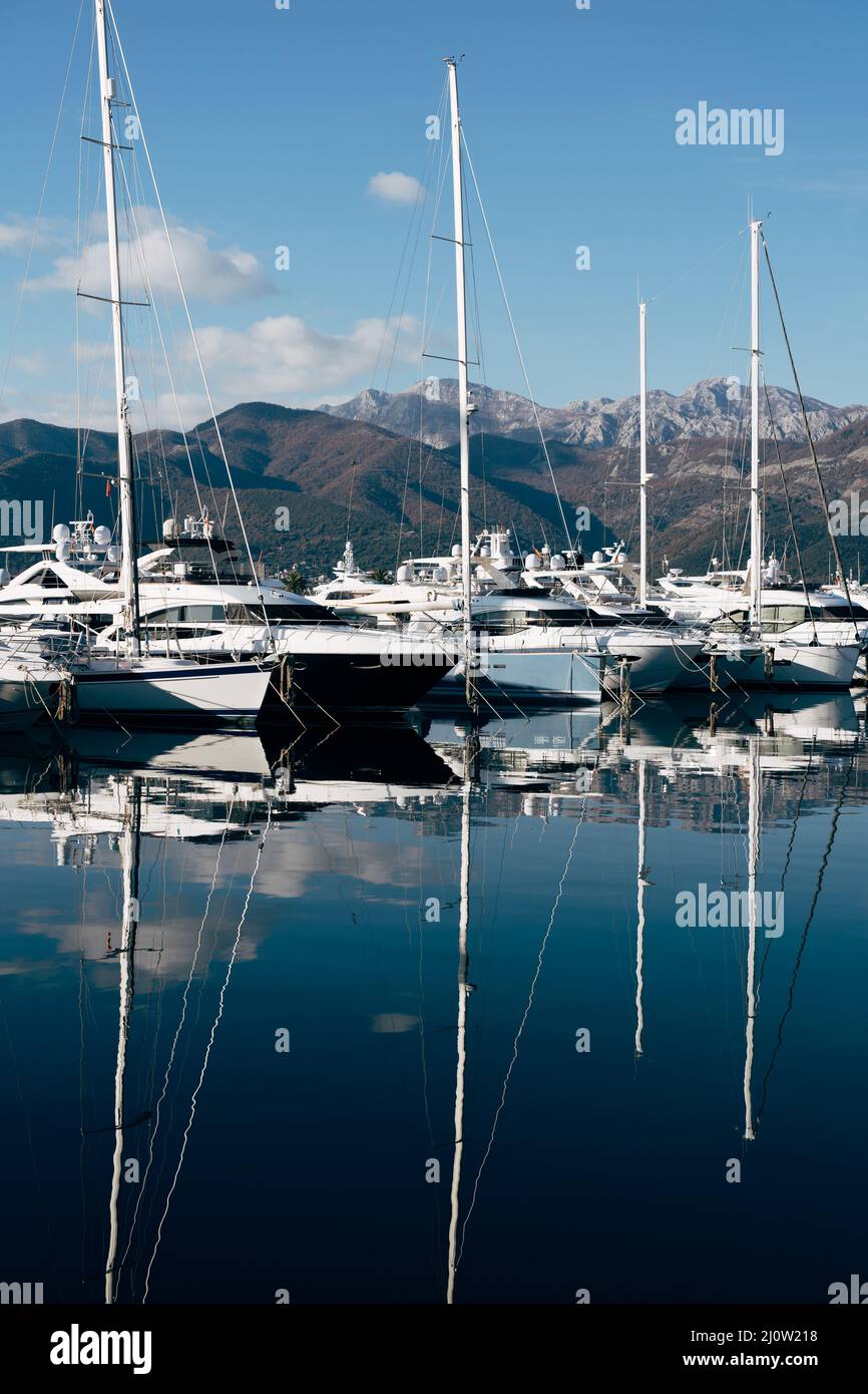 Sailing yachts are moored on the pier with the mountains in the background. Porto, Montenegro Stock Photo