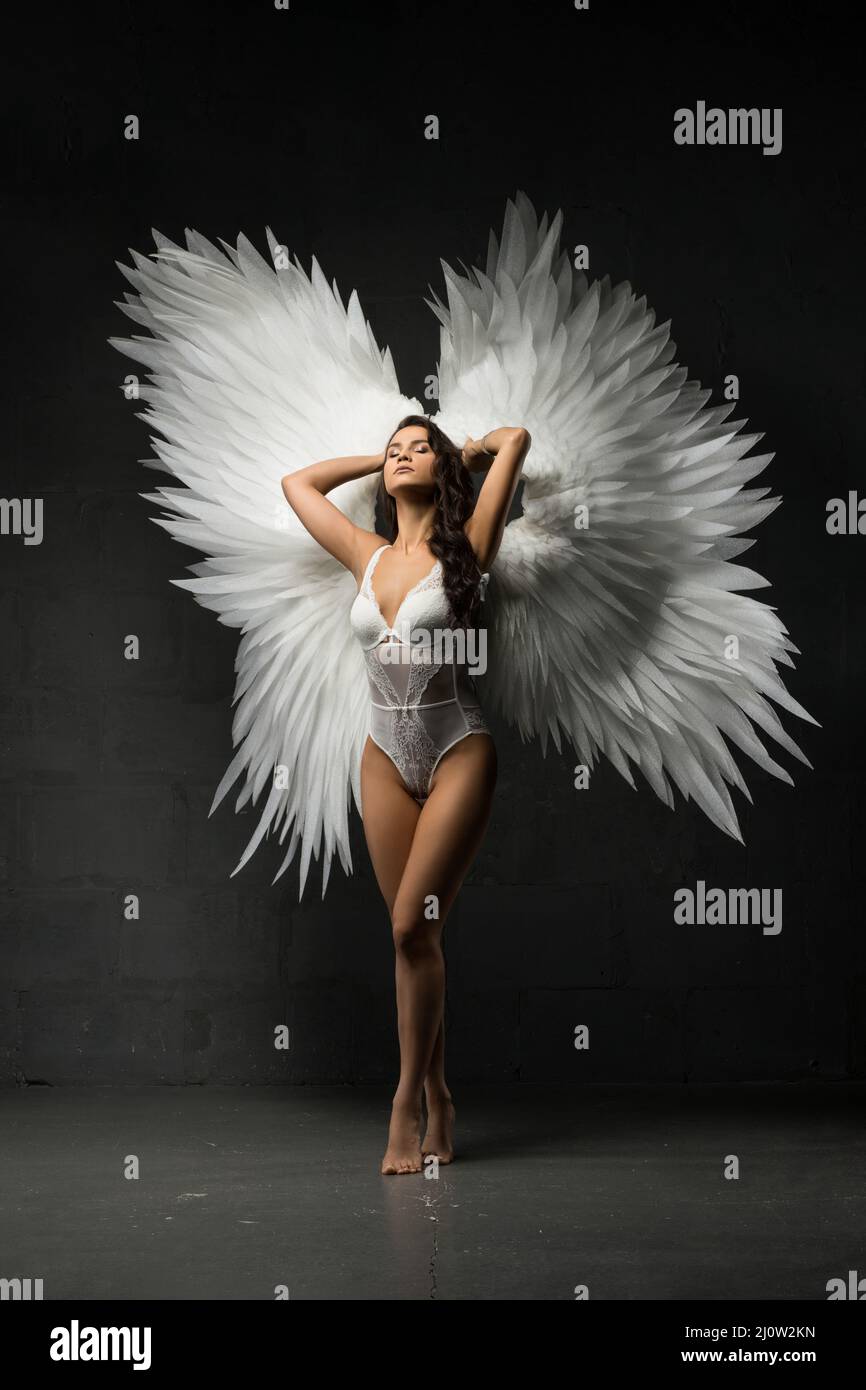 Slim woman in white bodysuit and feather wings Stock Photo