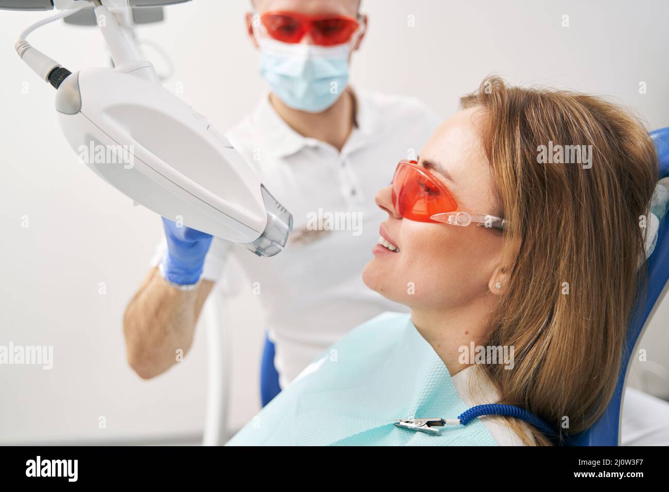 Woman having laser teeth whitening procedure in dental clinic Stock