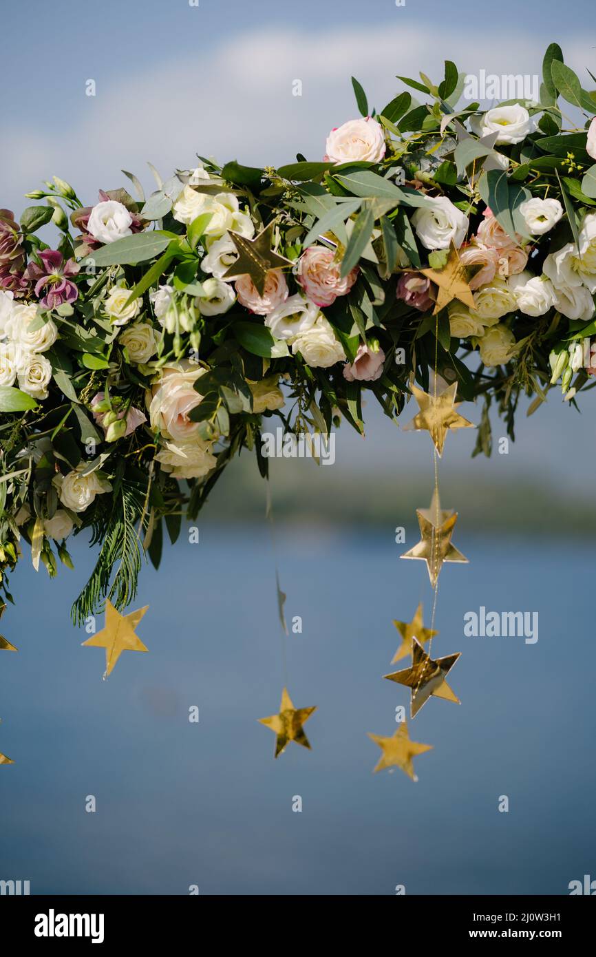 Fragment of a wedding arch, decorated with tea roses and gold stars Stock Photo