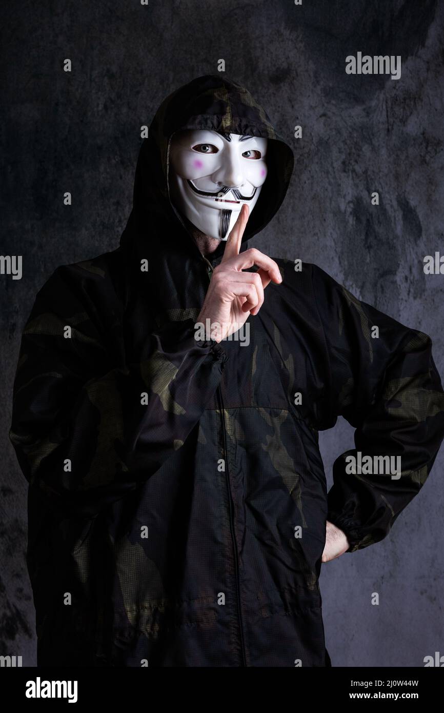 Midsection of a man wearing the mask of anonymous / Guy Fawkes and a camouflage uniform Stock Photo