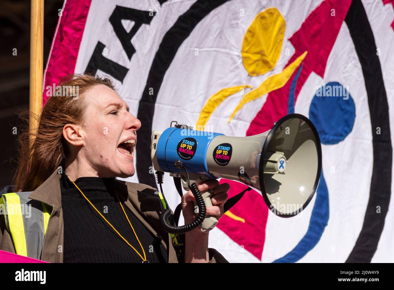 Protest taking place in London on UN Anti Racism Day. White, Caucasian female shouting into a loudhailer Stock Photo