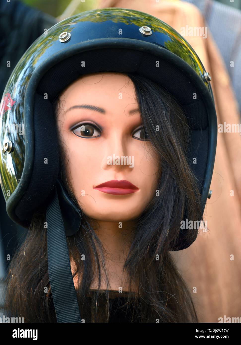 Mannequin head, found in flea market, has an intent and fixed glance.  Female head has long hair and motorcycle helmet Stock Photo - Alamy