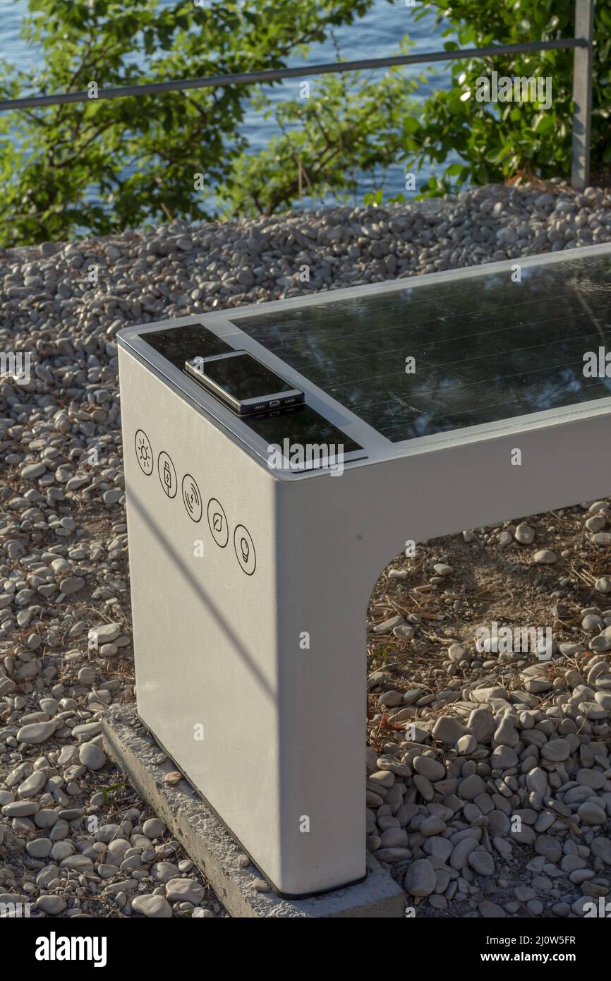 Smart Solar Bench in public place,  powered by sunlight provides wireless and wired charging for users, free wifi and temperatur Stock Photo