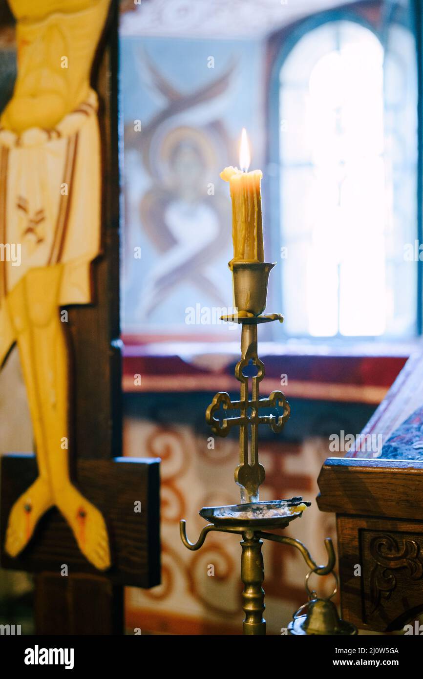 Wax candle on a candlestick near the crucifix in the temple Stock Photo