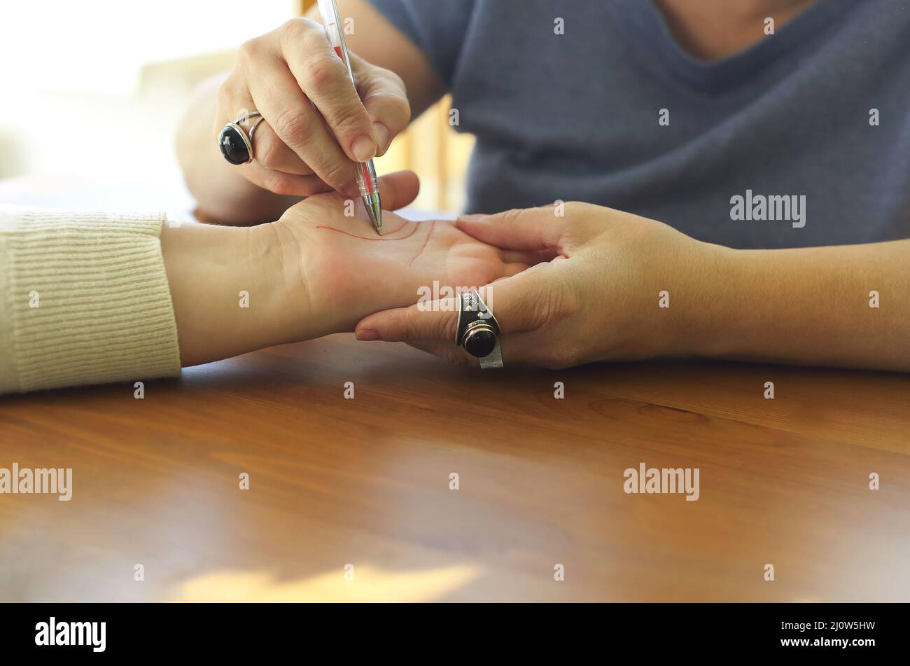 Palm Reading. Chiromancer drawing life lines on female plam during palmistry or chiromancy session Stock Photo