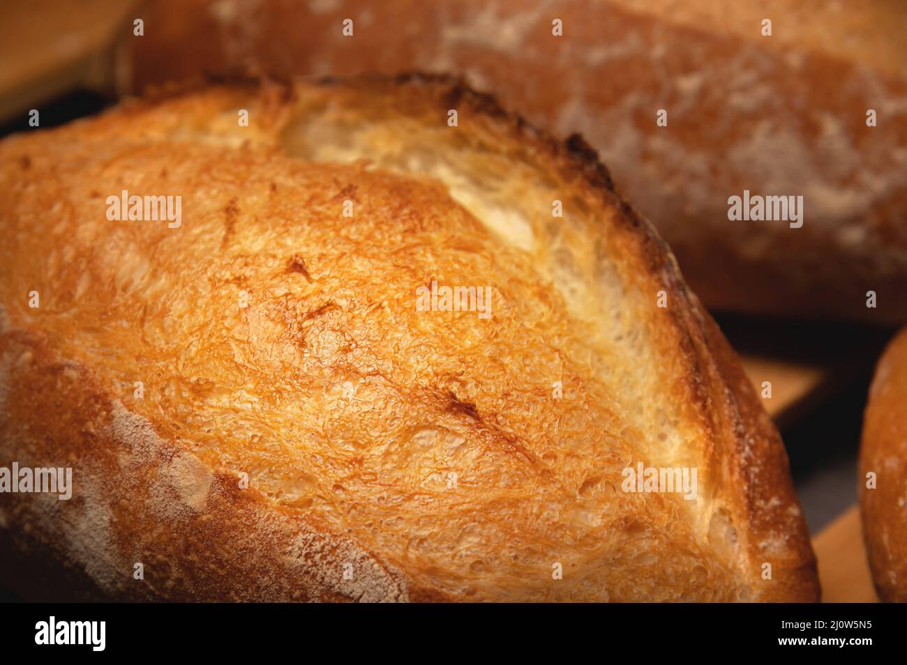 Appetizing fresh hot artisan bread. Close-up of a loaf of delicious bread on a wooden pallet Stock Photo