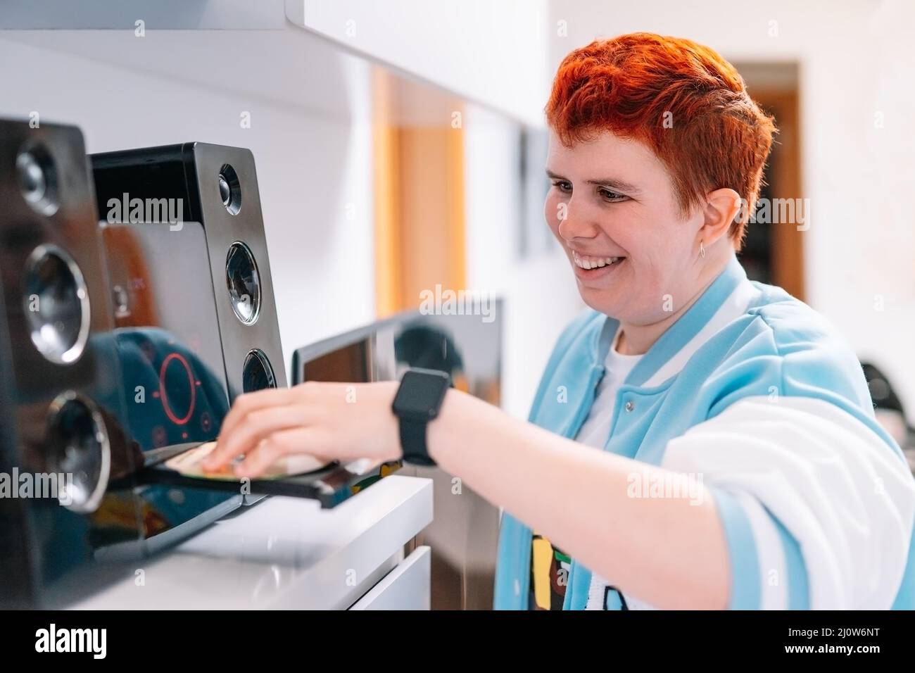 non-binary gender playing a CD on his mini-system to listen to music. Stock Photo