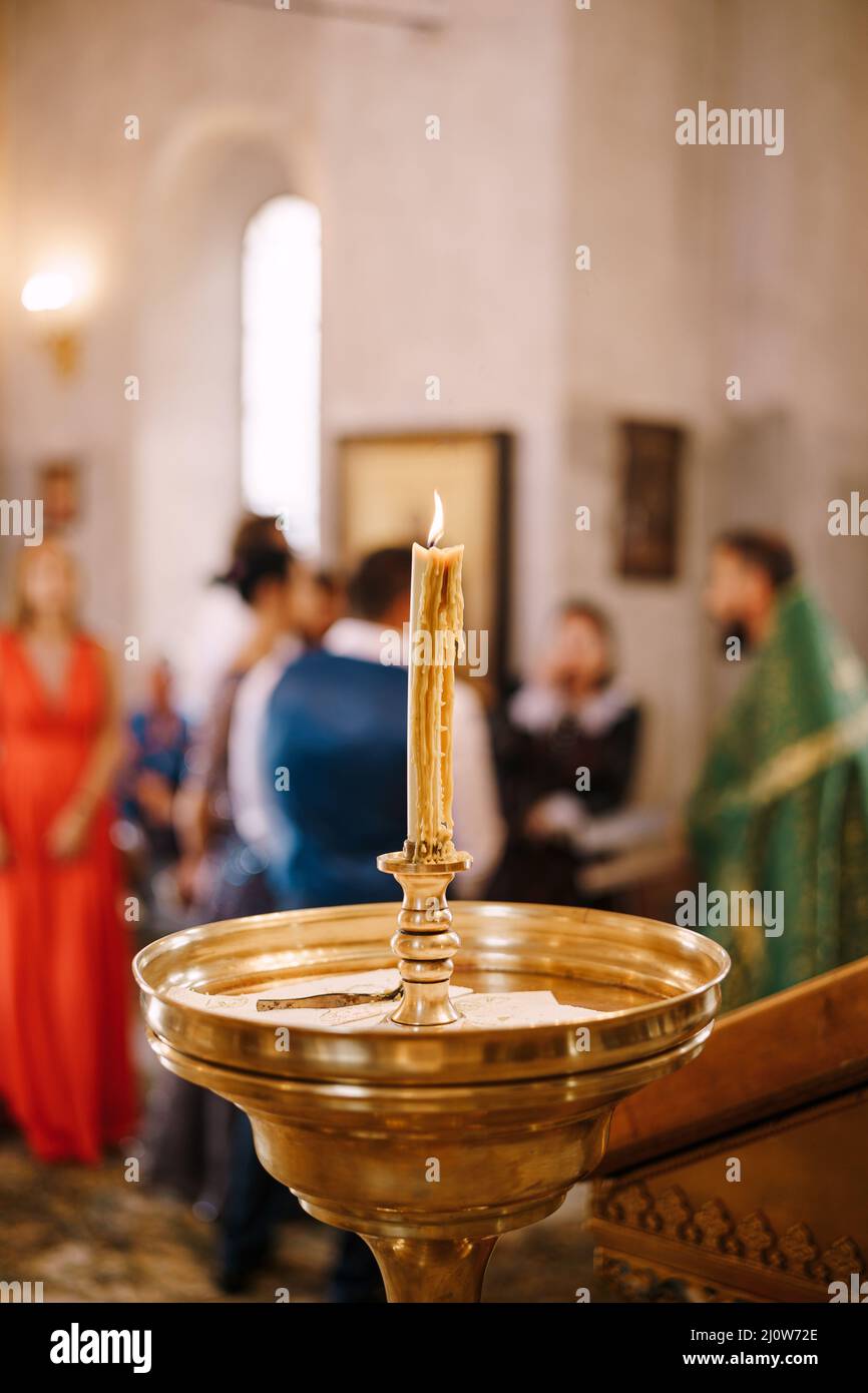 Wax candle burns on a stand in a large bowl in a temple Stock Photo