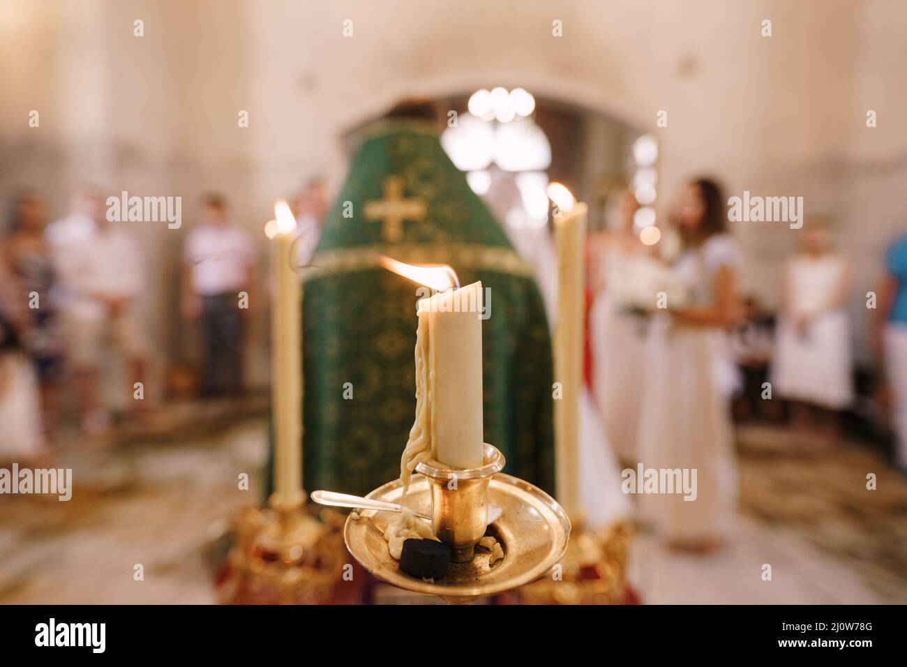 Candles burn on tall candlesticks during a wedding ceremony in a church Stock Photo