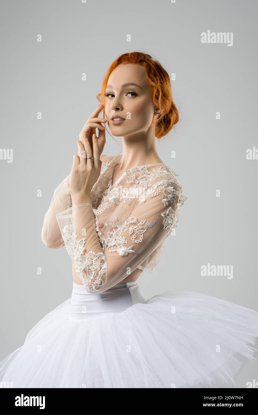 Alluring young ballerina in tutu touching face and looking at camera Stock Photo