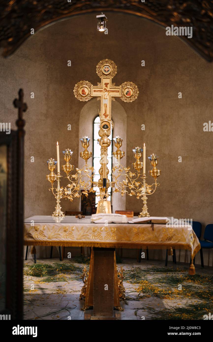 Branched gold candlestick on a table in front of a cross in the Church of St. Sava in Tivat Stock Photo