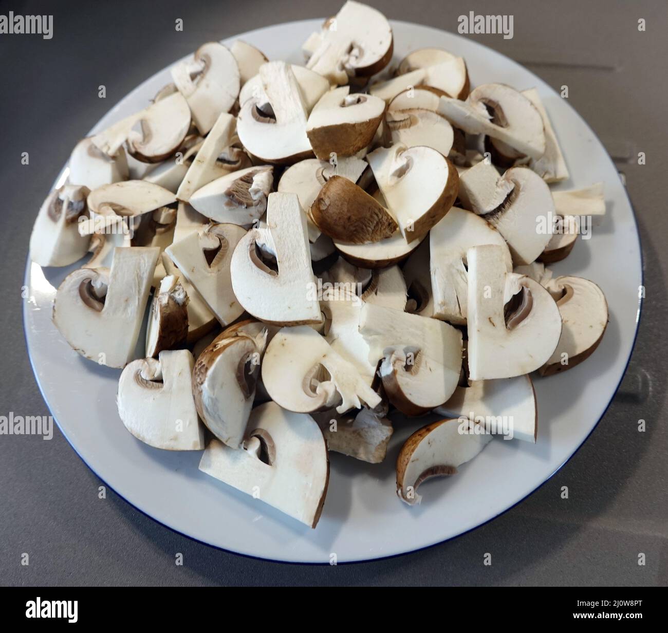 Fresh cultured mushrooms are sliced â€‹â€‹on a plate to fry Stock Photo