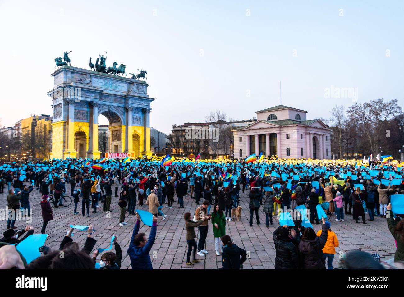 Milan, Italy - 03 19 2022: demonstration against Ukraine war at Peace Arch, Arco della Pace, illuminated with Ukraine flag colors, yellow and blue Stock Photo