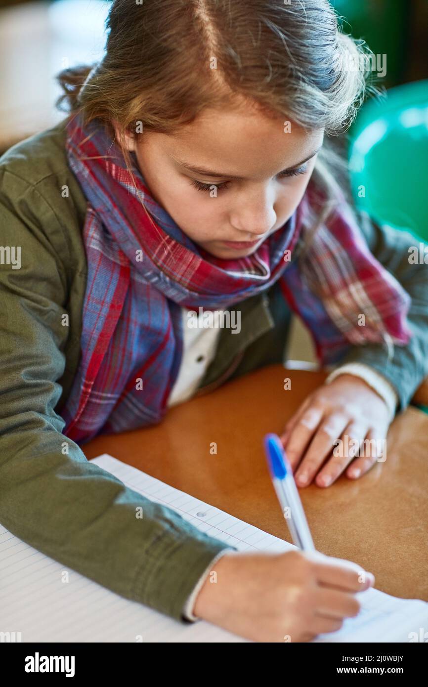 Shes all about finishing her schoolwork. Cropped shot of an elementary school girl doing her school work in the classroom. Stock Photo