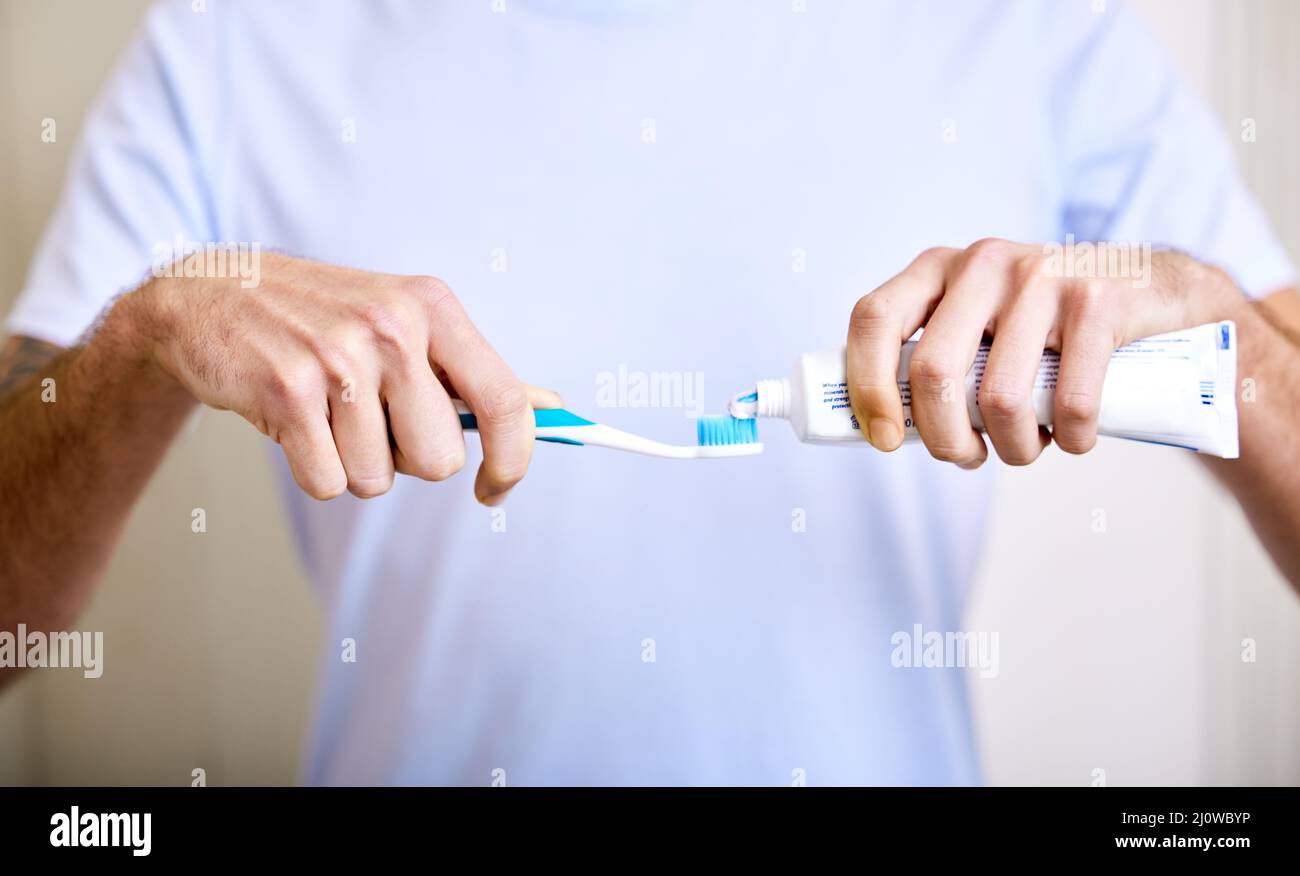 Brushing twice a day keeps the cavities away. Shot of a man applying ...