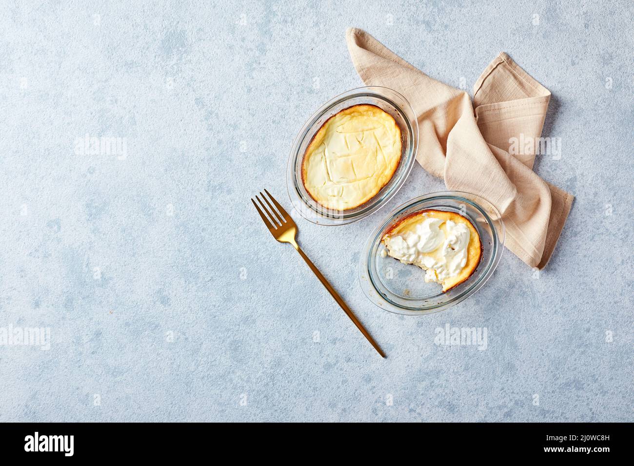 Delicious cottage cheese casserole in portioned glass forms with sour cream. Traditional Russian cuisine for breakfast - Zapekan Stock Photo