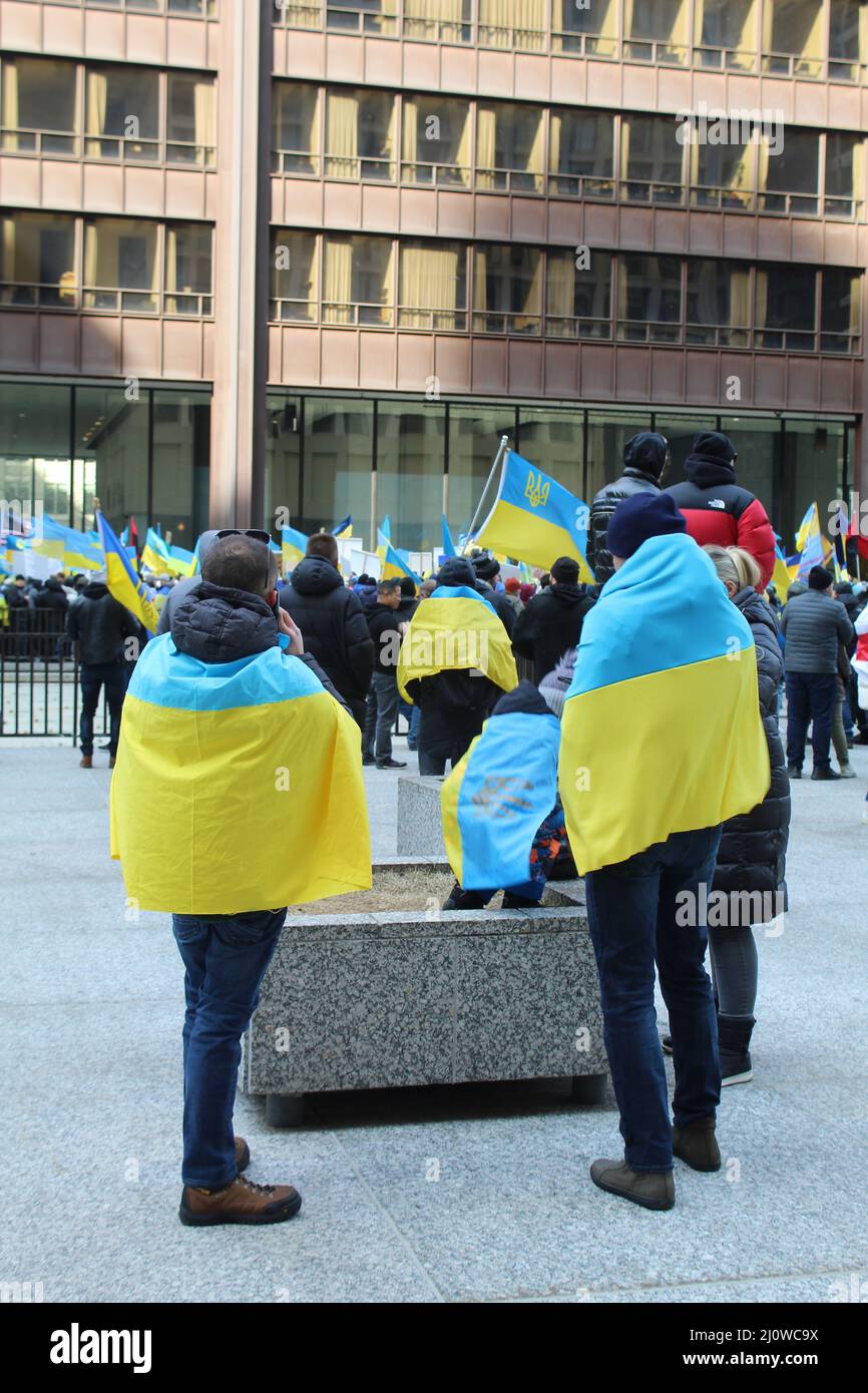 People wrapped in Ukrainian flags at an anti-war Daley Plaza protest in Chicago Stock Photo