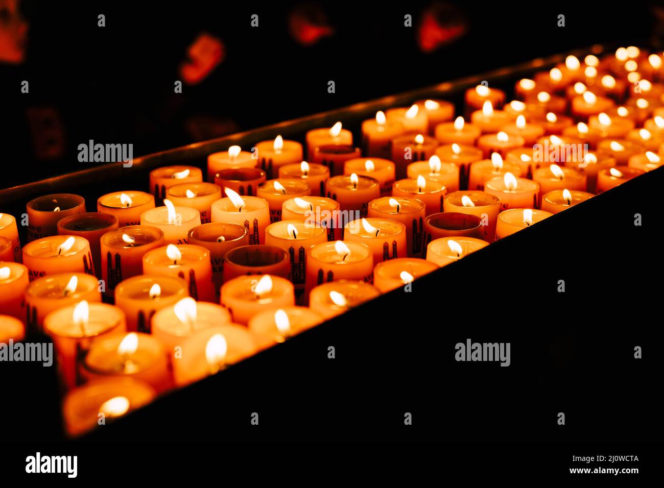 Votive candles burn on a stand in a church in the dark Stock Photo