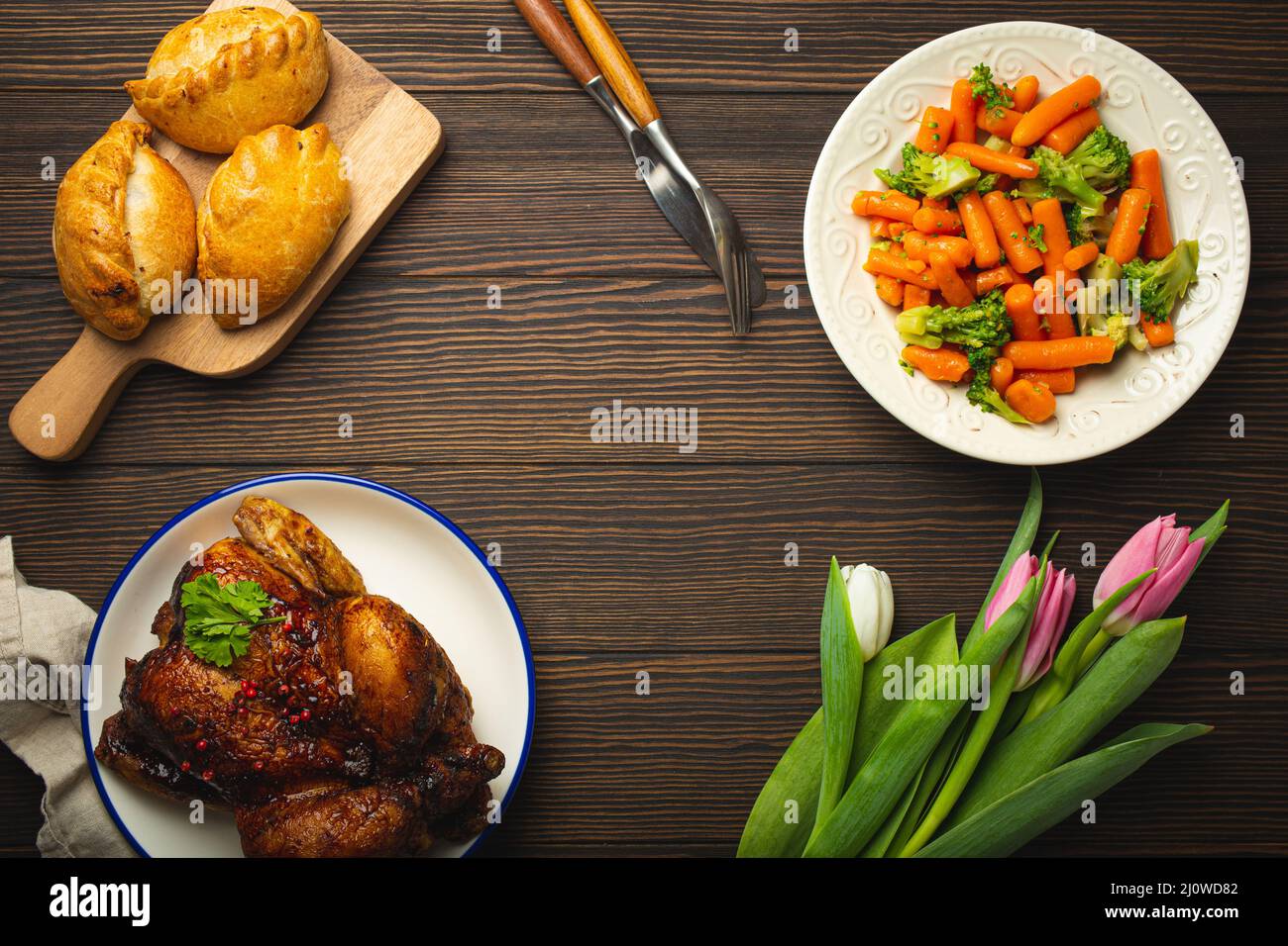 Easter food on dark rustic table: pastel colored eggs, roasted chicken ...