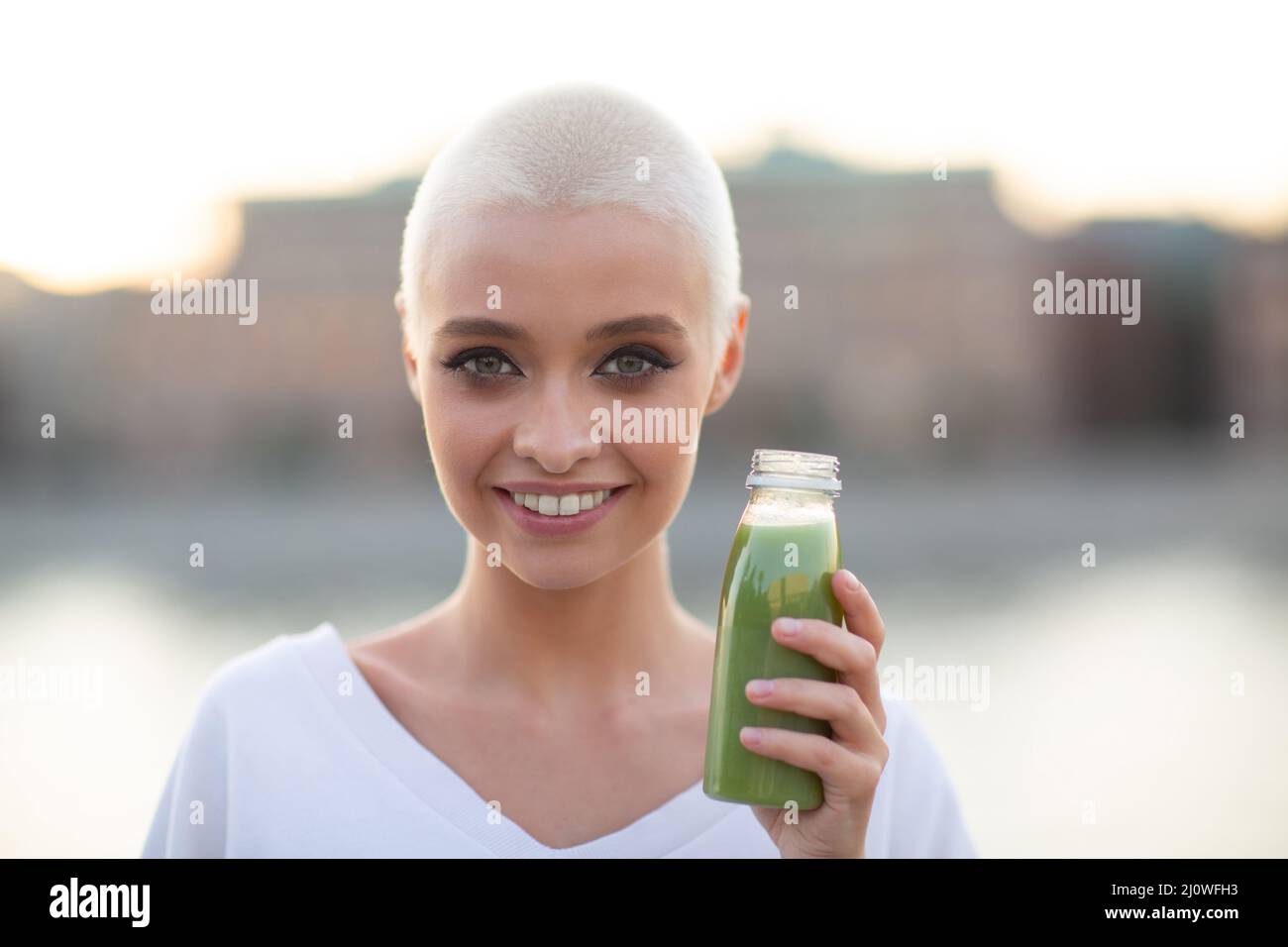 Millenial young woman blonde short hair outdoor with green smoothie Stock Photo