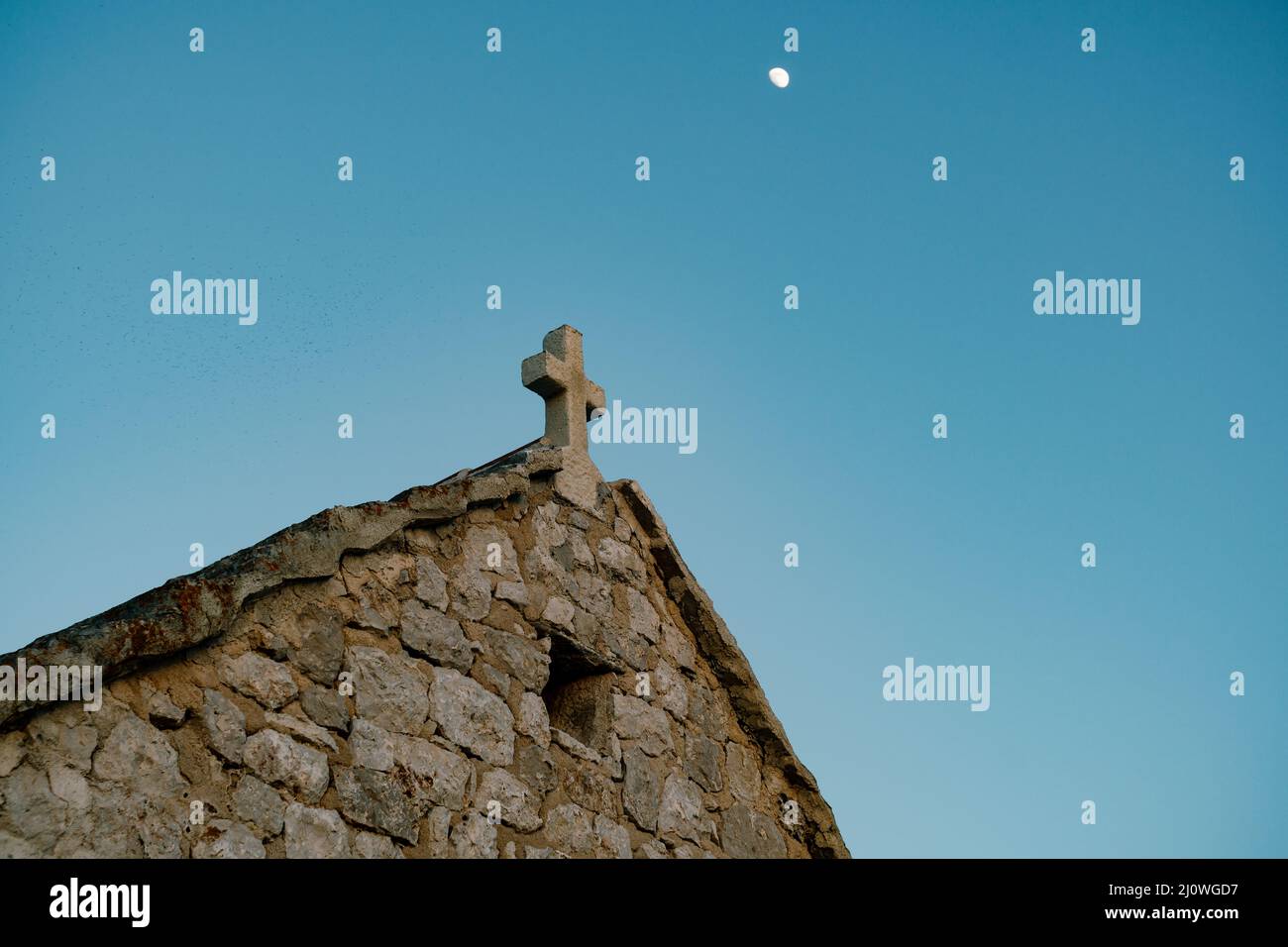 Roof of the old church of St. Ivan with a cross on the background of the sky. Cape Punta Planca Stock Photo