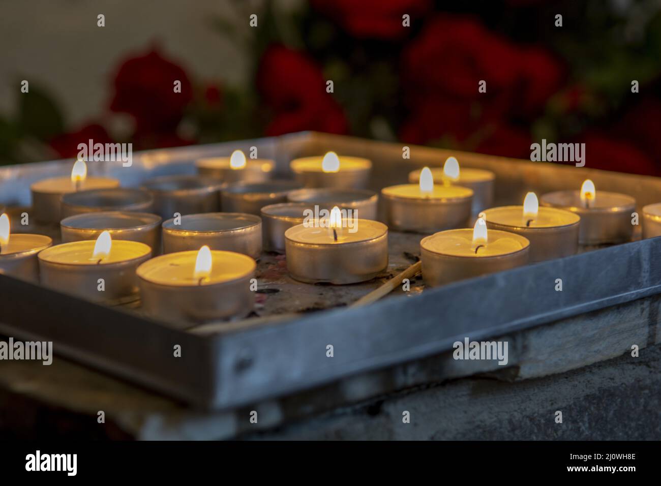 Burning prayer candles inside a catholic church. Lit tea lights. Selective focus. Stock Photo