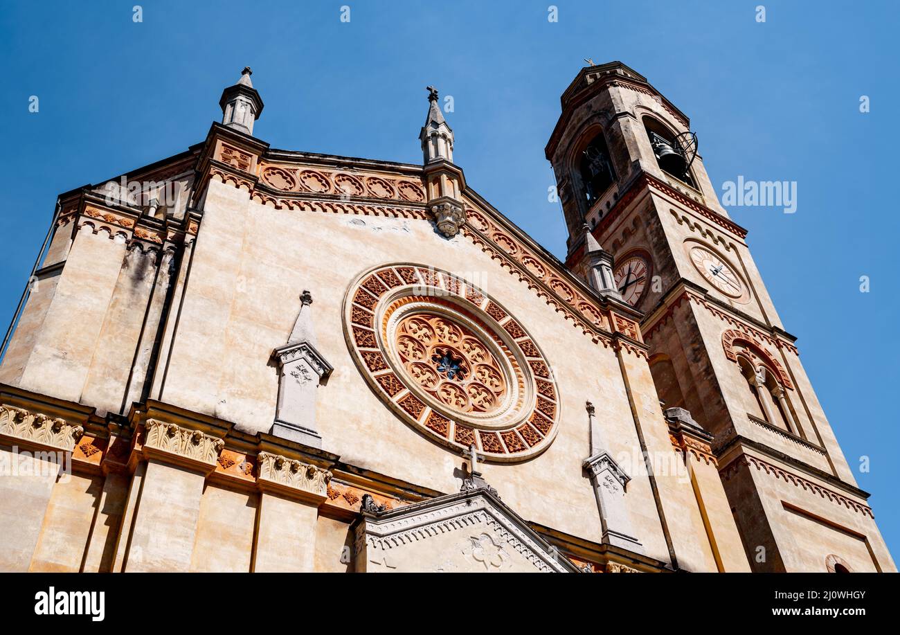 Facade of an old church with a belfry, a rose window and a clock on the tower Stock Photo