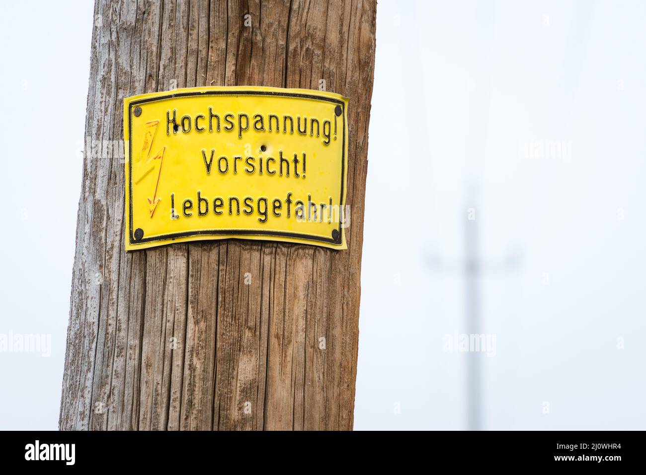 Electric pole warning sign in yellow Stock Photo