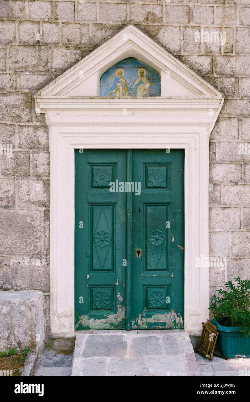 Green wooden door on the stone facade of the temple Stock Photo