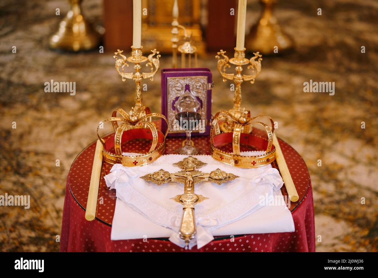 Cross, golden crowns and candlesticks stand on the table in the church Stock Photo