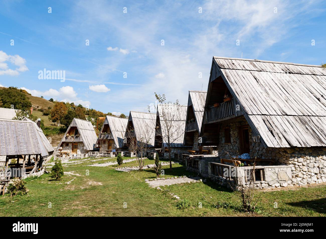 Triangular stone houses with wooden roofs against the backdrop of mountains. Montenegro Stock Photo