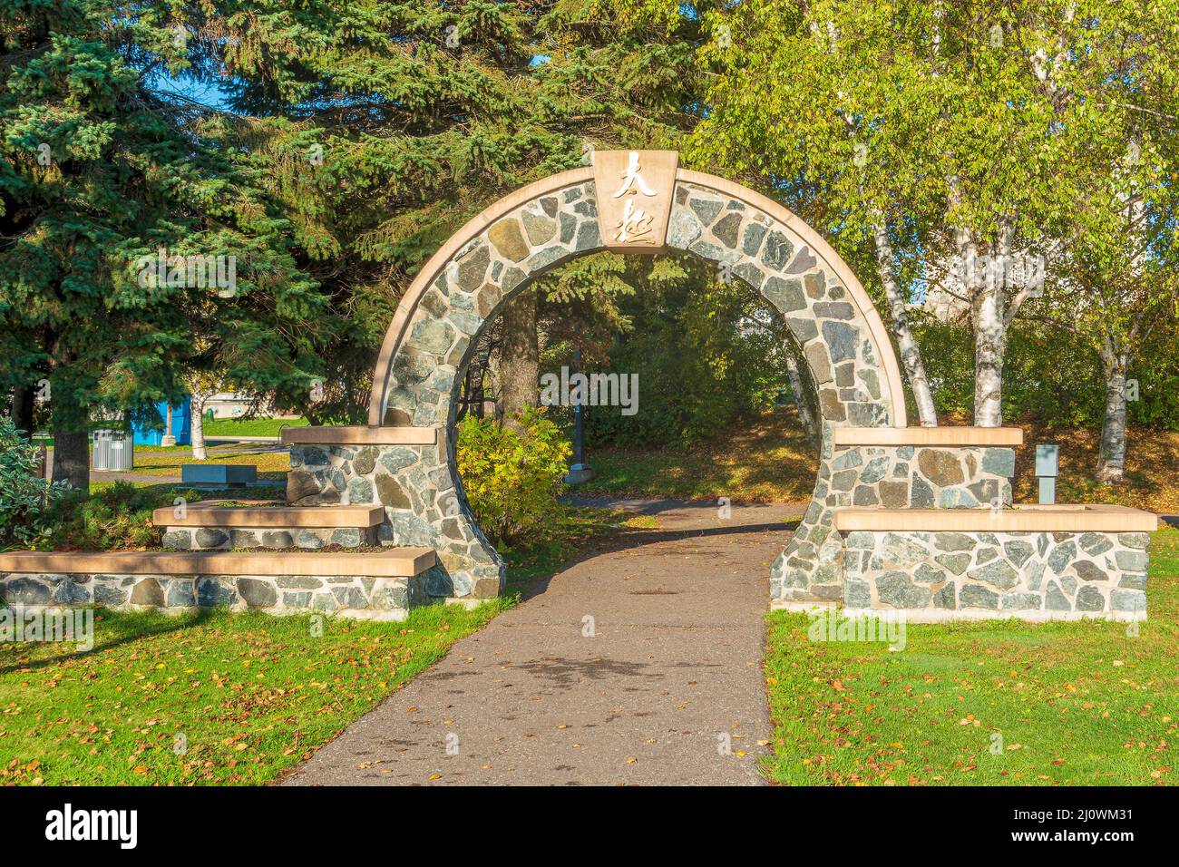 Stone arch with chinese inscription over the walkway leading into the Tai Chi Park at Prince Arthurs Landing in Thunder Bay Ontario. Stock Photo