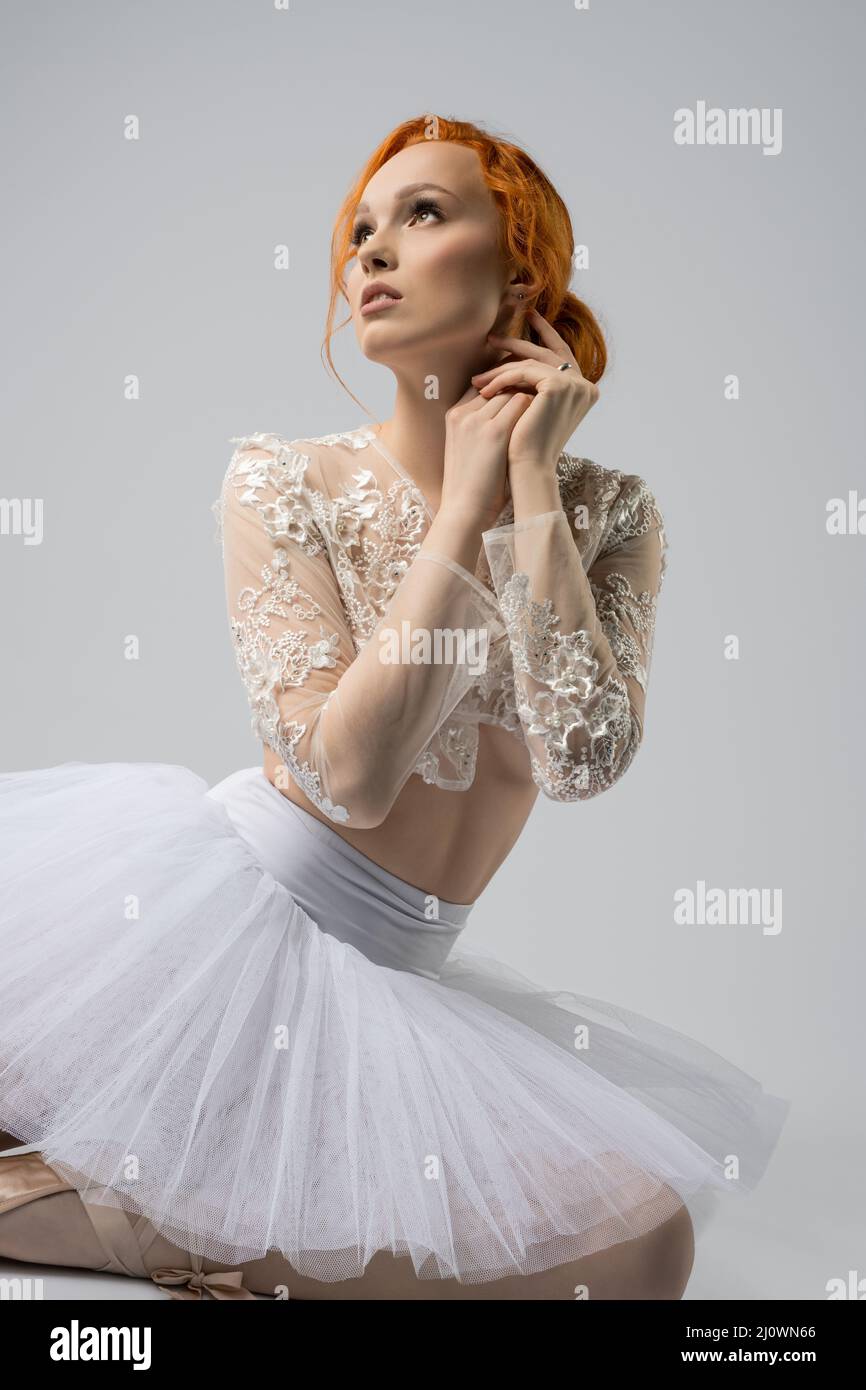 Graceful female ballet dancer sitting on floor and looking up Stock Photo