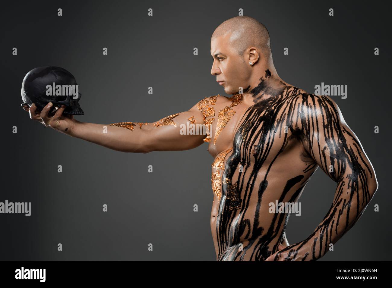 Serious nude man with skull in studio Stock Photo