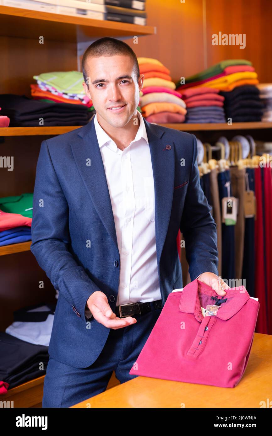Friendly salesman offering stylish polo shirt Stock Photo - Alamy - Offering A Stylish And