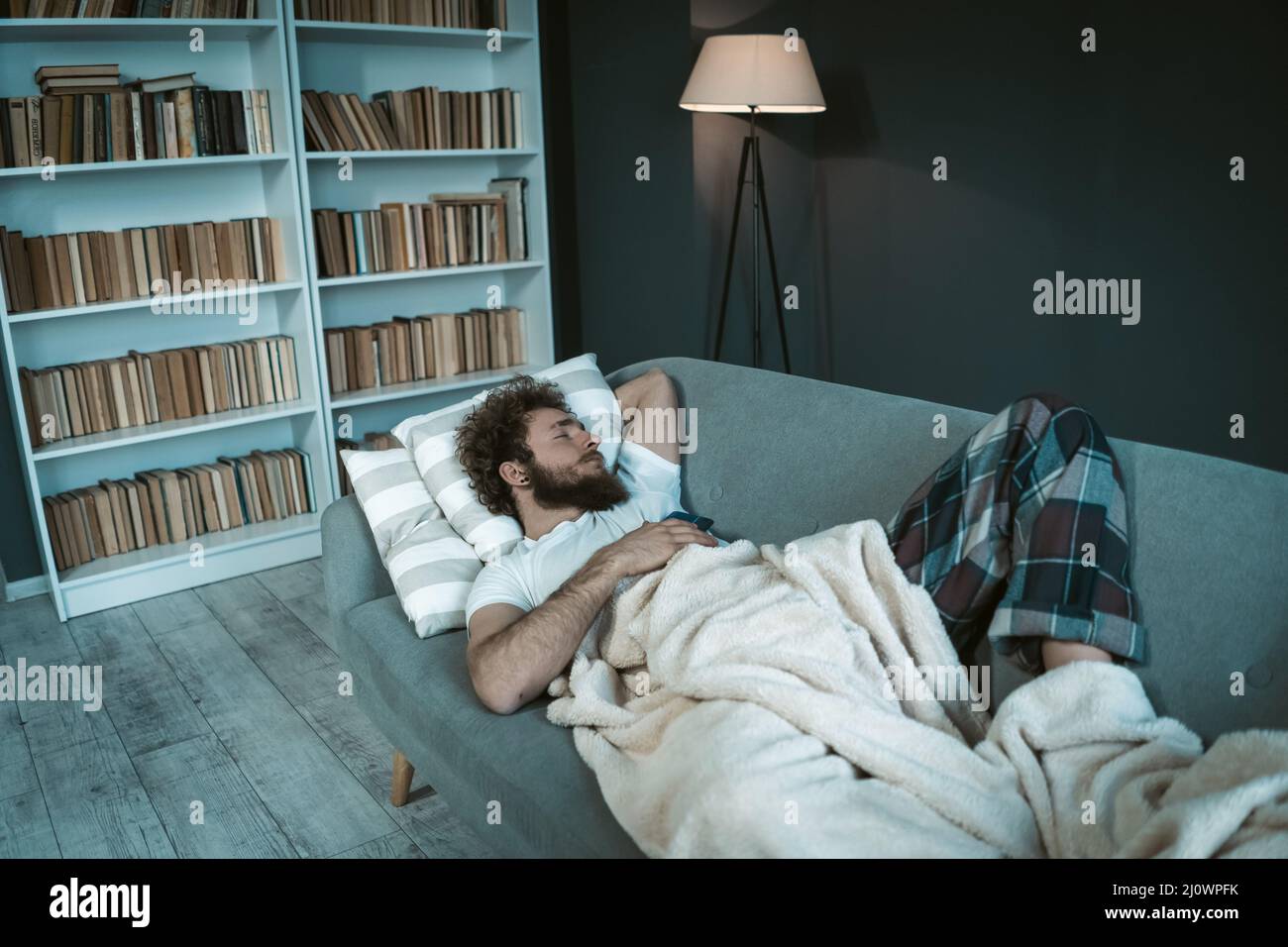 Male model sleeps on couch in her apartment. Concept of student life. Night, home comfort, bedtime. Stock Photo