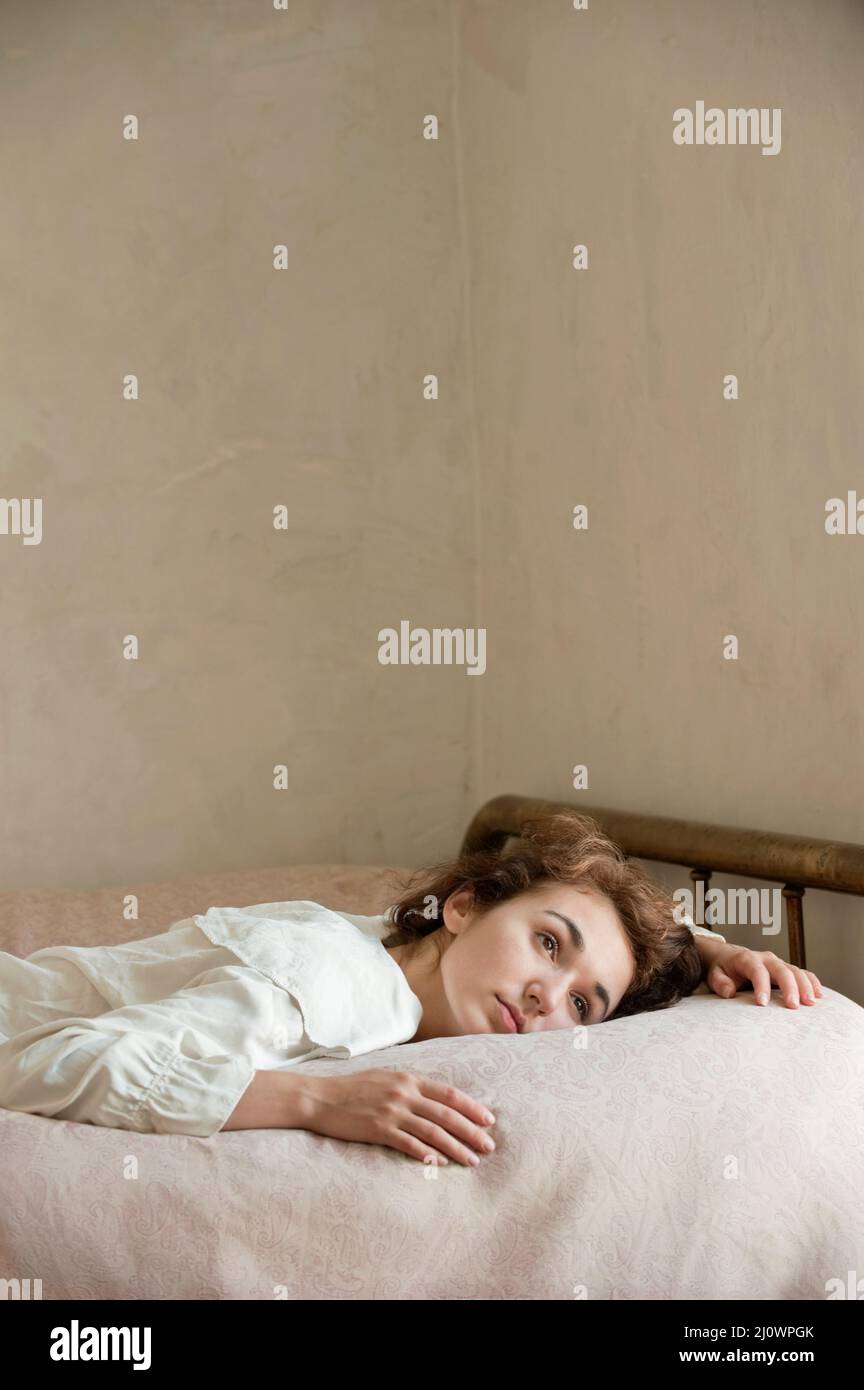 Young woman wearing white reclining in bed Stock Photo Alamy