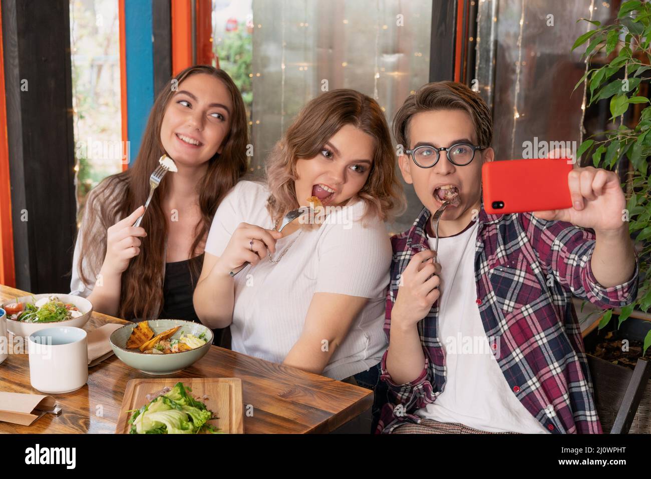 Freshmen in a cafe take a selfie. Teenage friends meeting for lunch. First year students spend leisure time together. Stock Photo