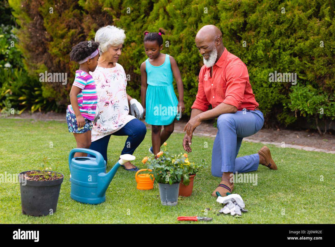 African american grandparents and grandchildren watering plants