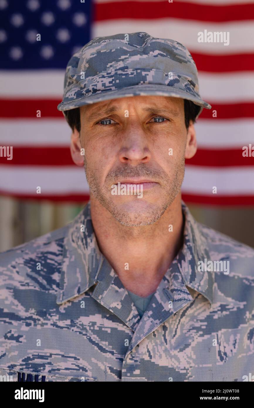Portrait of confident army soldier wearing cap and camouflage uniform against usa flag Stock Photo