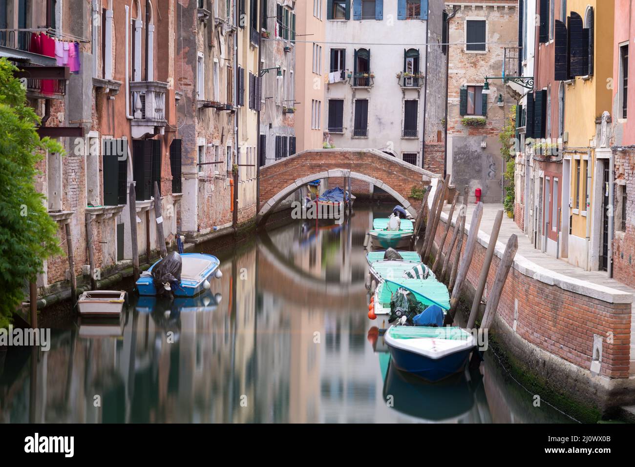 Small canal and bridge between houses in Venice, Italy Stock Photo