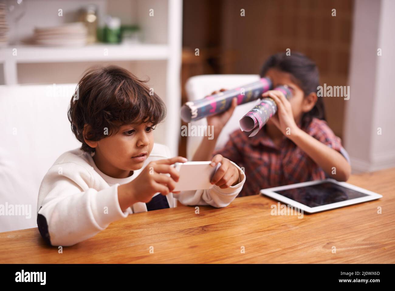 Hes going for a highscore... shes trying to distract him. Shot of two siblings having fun at home. Stock Photo