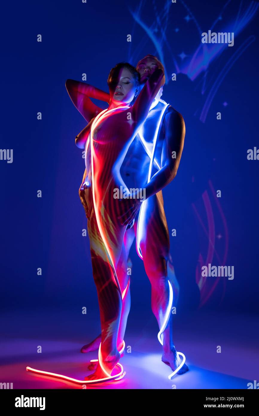 Naked couple wrapped with neon ropes and standing together Stock Photo
